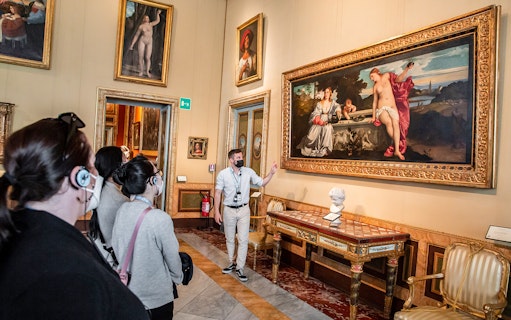 Tour group viewing artwork at Borghese Gallery, Rome, with guide explaining a large painting.
