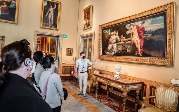 Tour group viewing artwork at Borghese Gallery, Rome, with guide explaining a large painting.
