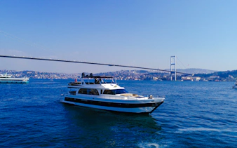 Cruise boat on the Bosphorus with Istanbul's bridge in the background.