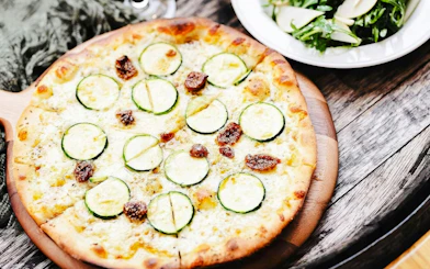 Zucchini and fig pizza served on a wooden board during Yarra Valley Winery Tour.