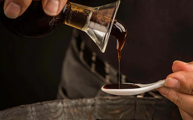 Pouring vinegar into a tasting spoon during a guided cellar tour.