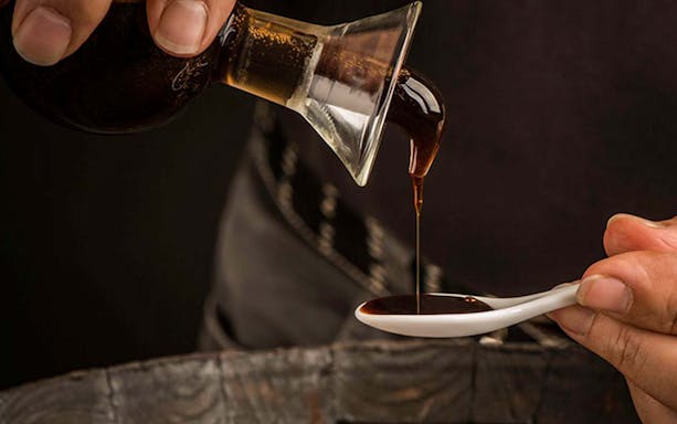 Pouring vinegar into a tasting spoon during a guided cellar tour.