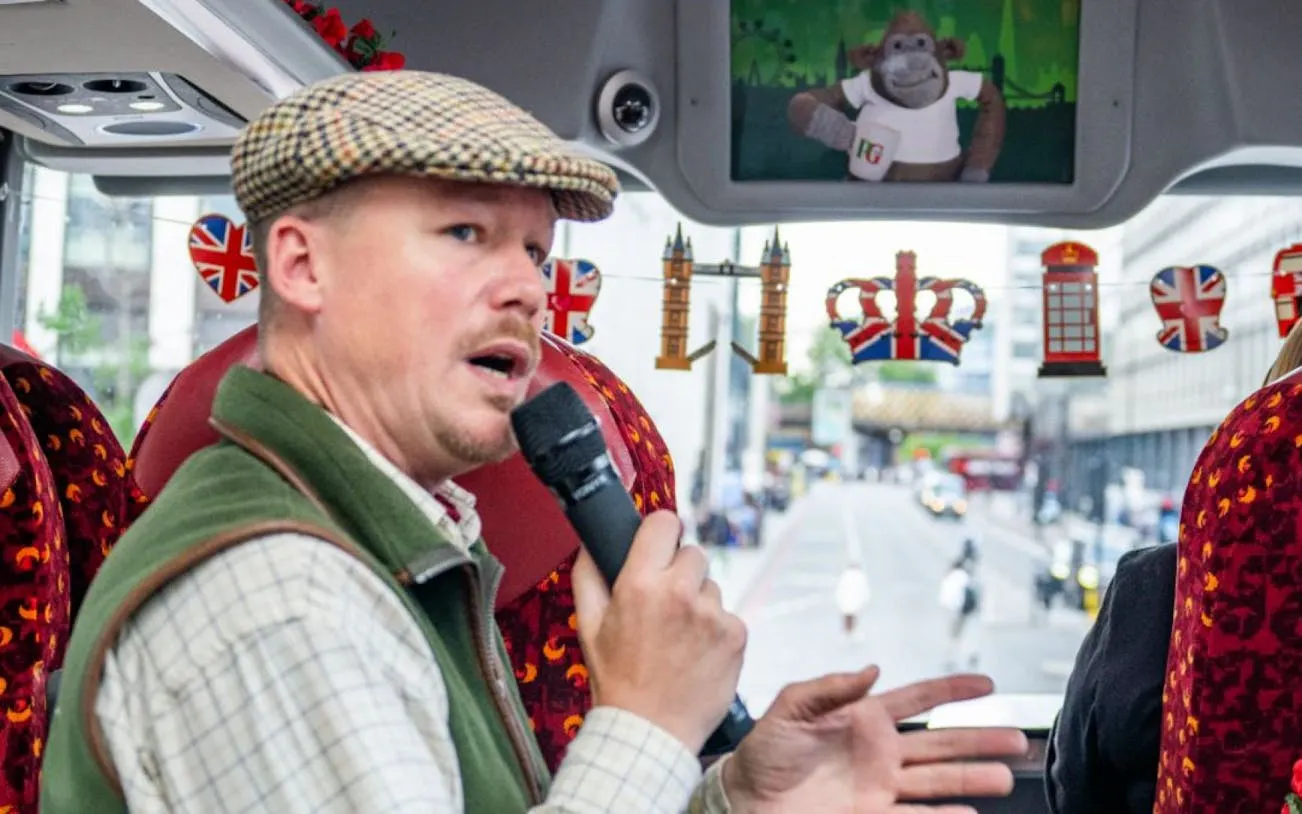 Tour guide speaking on a London sightseeing bus with British-themed decorations.