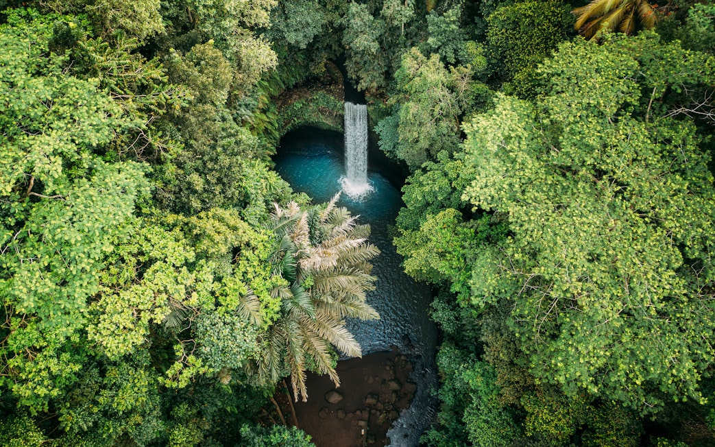 Tibumana waterfall surrounded by lush green forest in Bali, Indonesia.