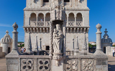 Belém Tower in Lisbon with tourists exploring the ornate stone carvings and historic architecture.