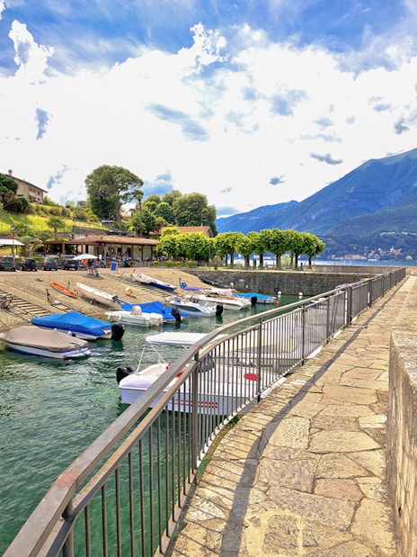 Boats docked at Punta Spartivento viewpoint, Belaggio, with Como Lake and mountains in the background.