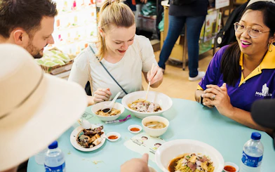 Tourists enjoying local dishes on a guided Michelin and hawker food tour.