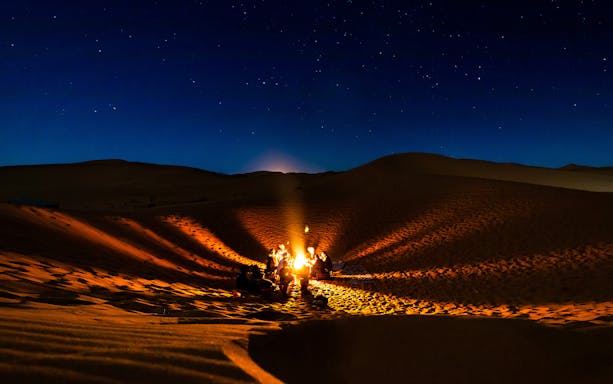 Starry night desert campfire in Hurghada with group dining.