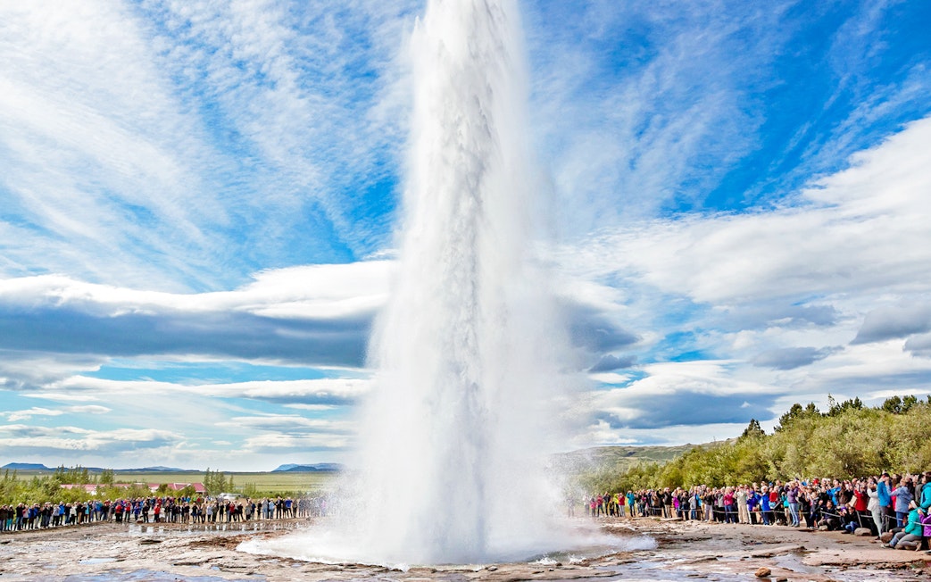 Strokkur geyser erupting in Golden Circle, Iceland, with tourists watching.