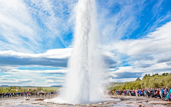 Strokkur geyser erupting in Golden Circle, Iceland, with tourists watching.