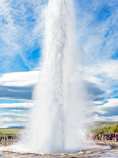 Strokkur geyser erupting in Golden Circle, Iceland, with tourists watching.