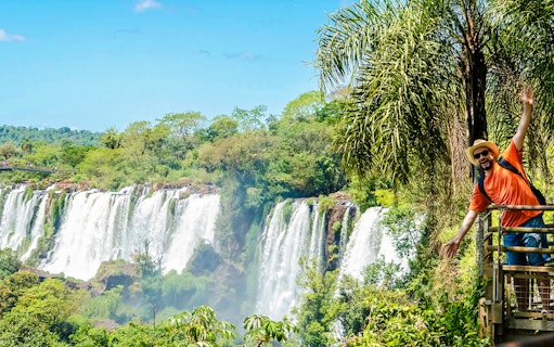 Tourist posing on a platform with Iguazu Falls in the background, Argentina.