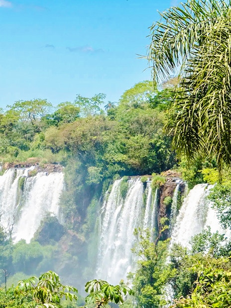 Tourist posing on a platform with Iguazu Falls in the background, Argentina.