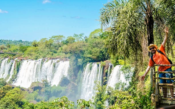 Tourist posing on a platform with Iguazu Falls in the background, Argentina.