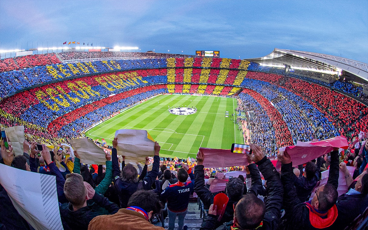 Crowd at FC Barcelona's Camp Nou stadium displaying team colors during a match.
