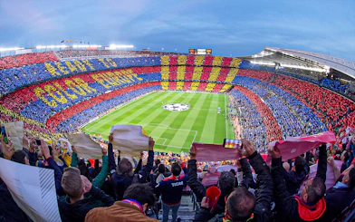 Crowd at FC Barcelona's Camp Nou stadium displaying team colors during a match.