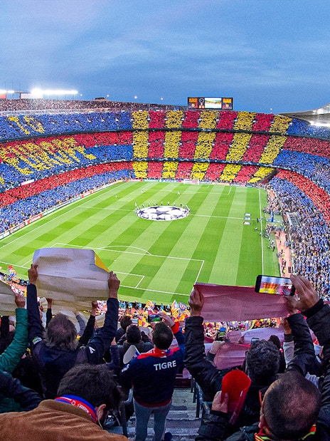 Crowd at FC Barcelona's Camp Nou stadium displaying team colors during a match.
