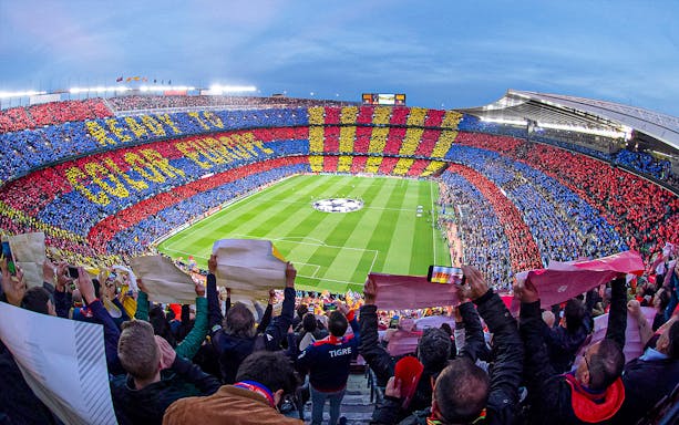 Crowd at FC Barcelona's Camp Nou stadium displaying team colors during a match.