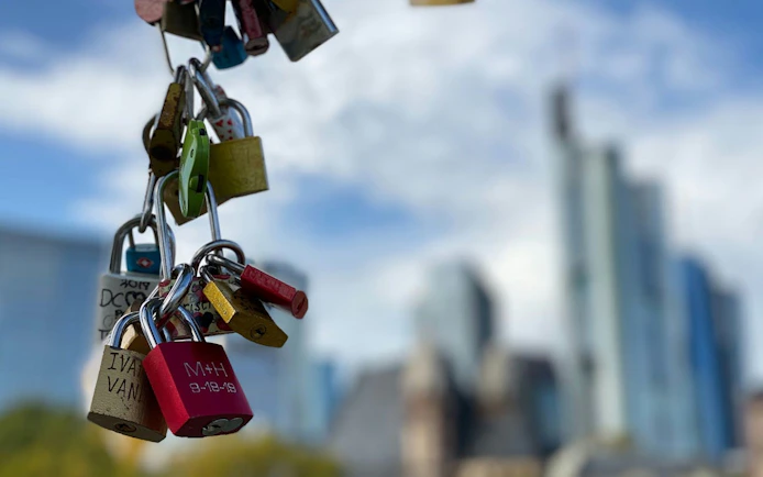 Love locks hanging with Frankfurt skyline in the background.
