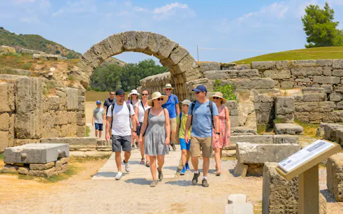 Visitors walking through ancient stone archway at Olympia Stadium, Greece.