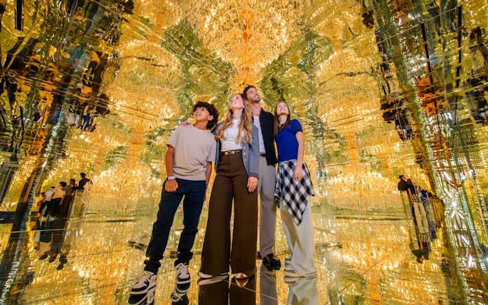 Family exploring mirrored room with golden lights at House Of Hype.