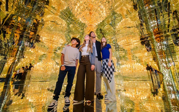 Family exploring mirrored room with golden lights at House Of Hype.