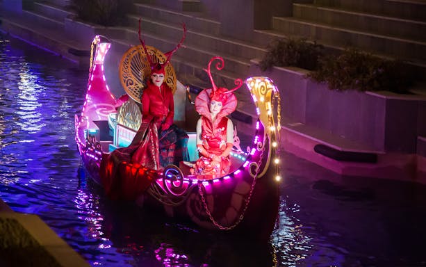 Colorful boat parade with performers in vibrant costumes at Land of Legends, Antalya, Turkey.
