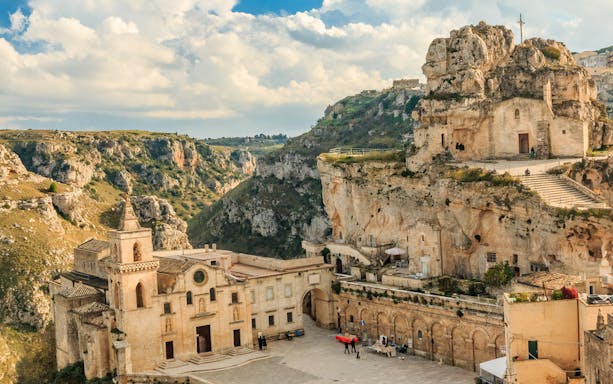 Matera's ancient rock church and historic buildings in a scenic landscape.