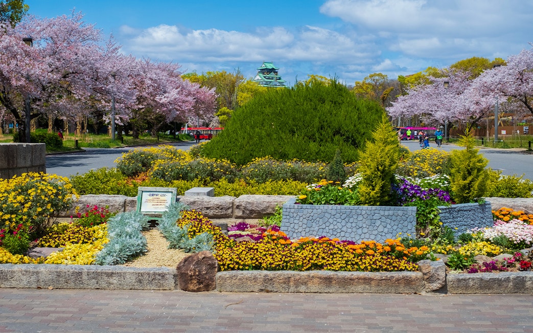 Osaka Castle with surrounding gardens and colorful flowers in bloom.