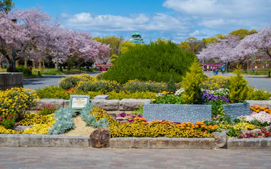 Osaka Castle with surrounding gardens and colorful flowers in bloom.