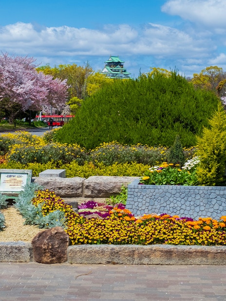 Osaka Castle with surrounding gardens and colorful flowers in bloom.