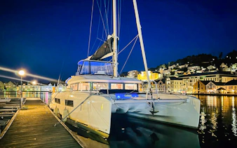 Luxury Catamaran Arctic Princess docked at night in a scenic harbor.