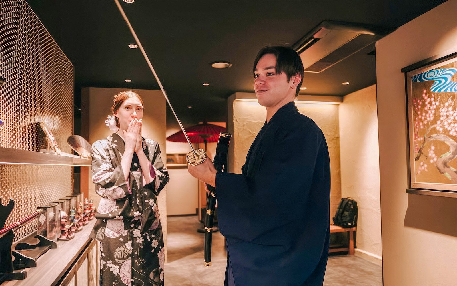 Tourists in traditional attire exploring Japanese swords indoors.