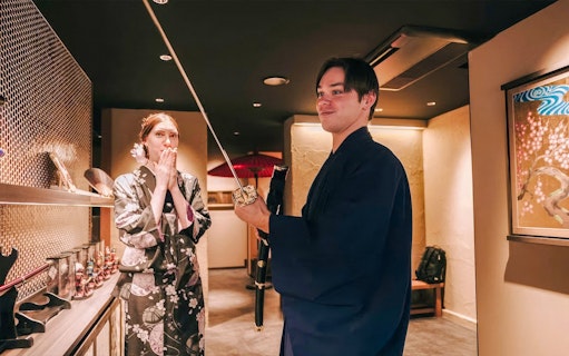Tourists in traditional attire exploring Japanese swords indoors.
