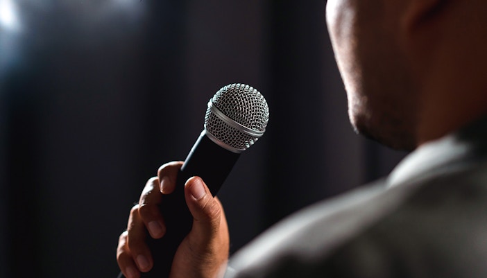 Man holding a microphone during a standup comedy performance.