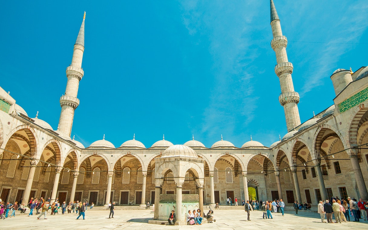 Blue Mosque courtyard with visitors, Istanbul, minarets in view.