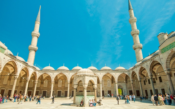 Blue Mosque courtyard with visitors, Istanbul, minarets in view.