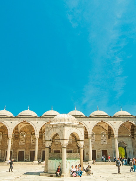 Blue Mosque courtyard with visitors, Istanbul, minarets in view.