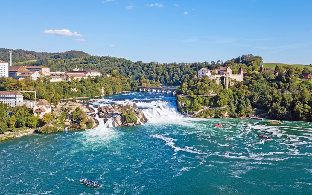 Panoramic aerial view of Rhine Falls, Switzerland, with surrounding buildings and lush greenery.