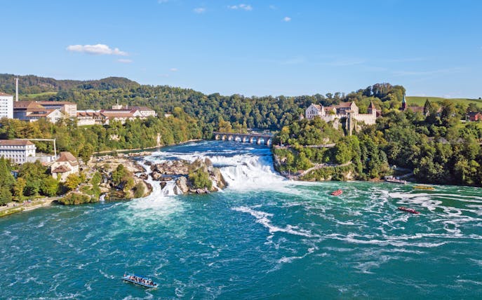 Panoramic aerial view of Rhine Falls, Switzerland, with surrounding buildings and lush greenery.