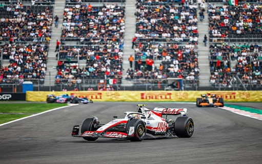 Race cars on track at Formula 1 Mexico Grand Prix with spectators in the stands.