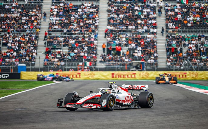 Race cars on track at Formula 1 Mexico Grand Prix with spectators in the stands.
