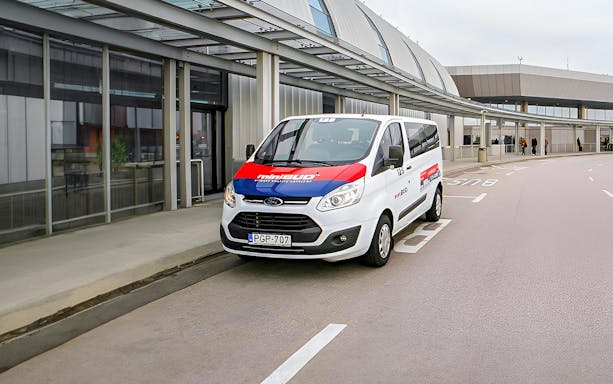 MiniBud Airport shuttle parked at airport terminal entrance.