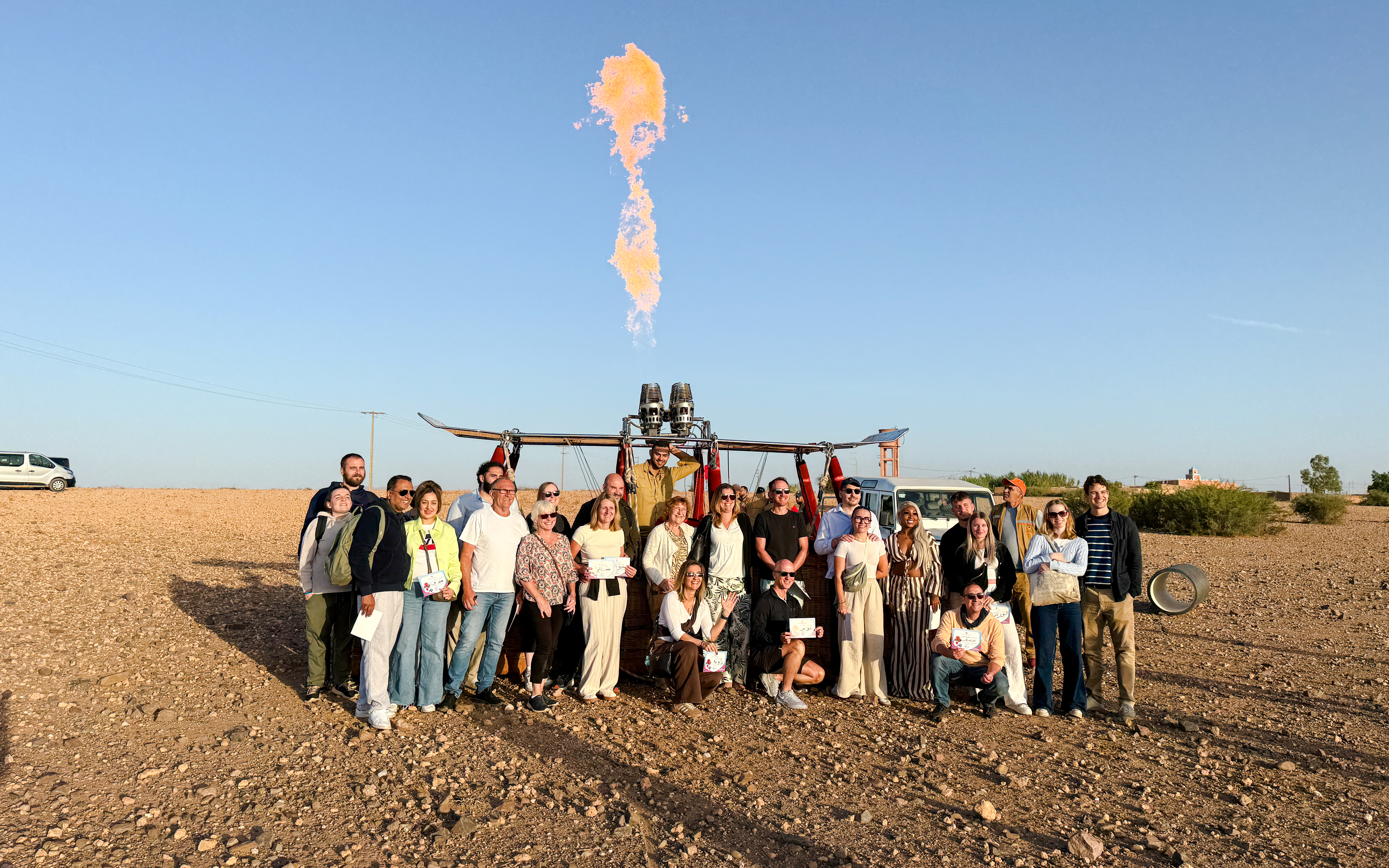 Group posing with hot air balloon in Marrakech desert.