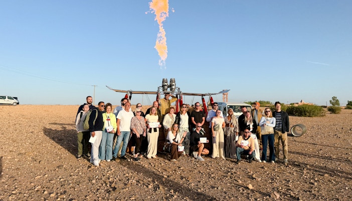 Group posing with hot air balloon in Marrakech desert.