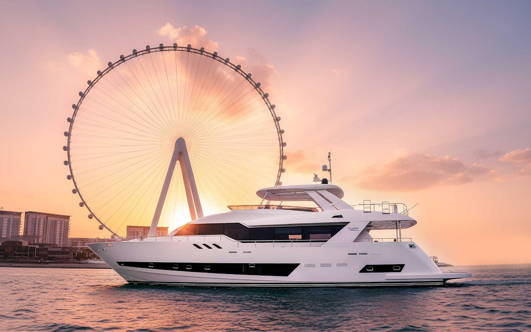 Yacht cruising near Ain Dubai Ferris wheel at sunset.