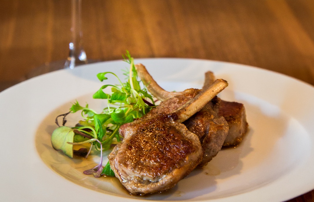 Grilled lamb chops with greens on a plate.