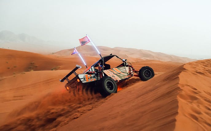 Dune buggy ascending a sand dune during a desert safari.