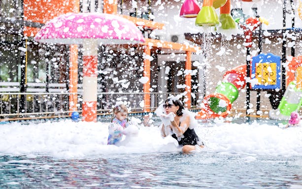Children playing in the splash pad area at Rawai Kids Park, Phuket, Thailand.