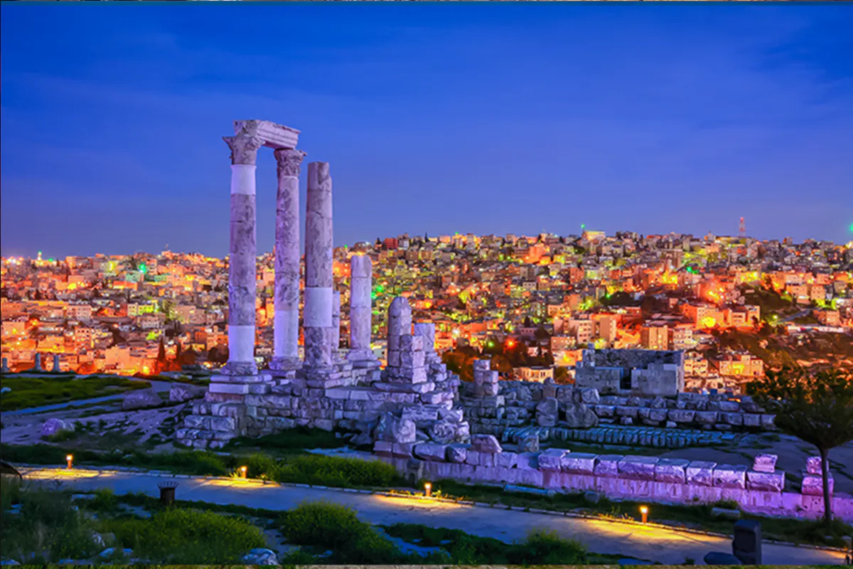 Roman Temple of Hercules ruins overlooking Amman cityscape at dusk.